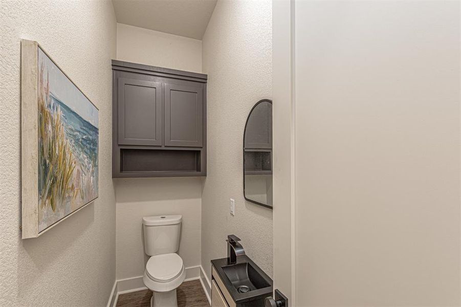 Half bath featuring a textured wall and dark wood-style floors