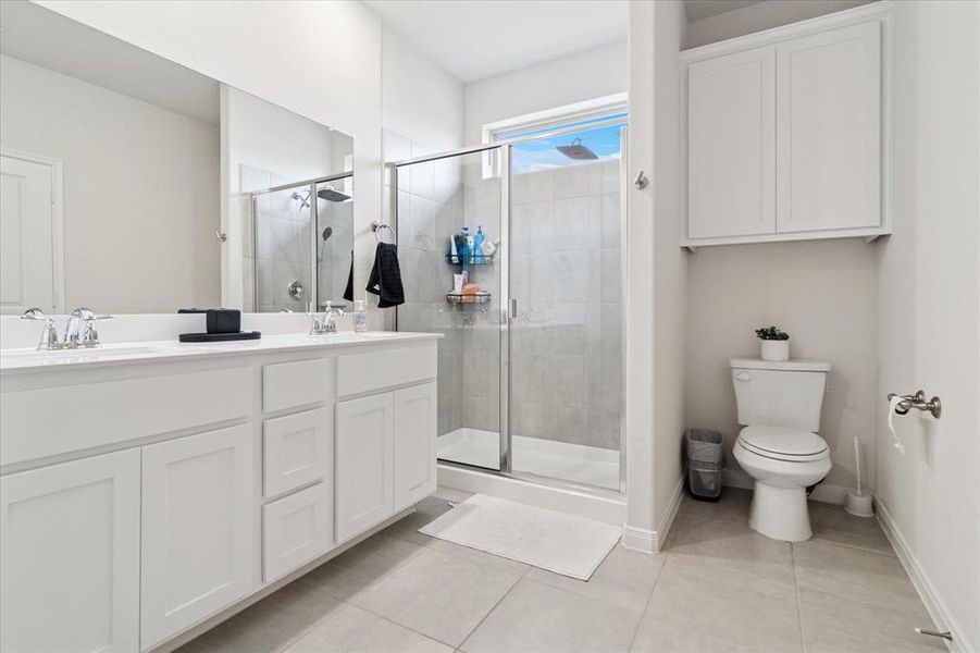 Full bath featuring light tile patterned flooring, double vanity, and a shower stall Full bath featuring light tile patterned flooring, double vanity, and a shower stall