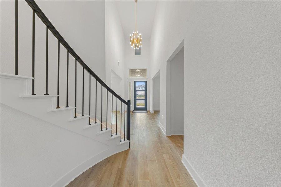 Entrance foyer featuring light wood finished floors, a towering ceiling, stairs, and a chandelier Entrance foyer featuring light wood finished floors, a towering ceiling, stairs, and a chandelier