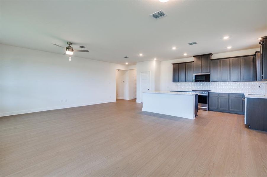 Kitchen featuring tasteful backsplash, stainless steel appliances, a kitchen island, light countertops, and a ceiling fan