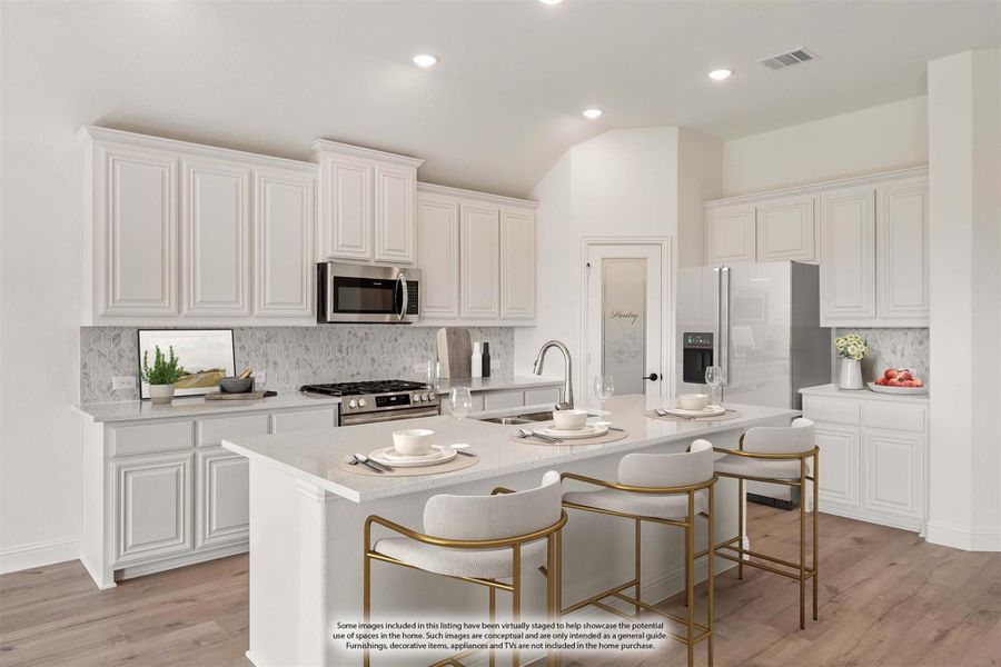 White kitchen with center island, three bar stools, stainless steel appliances, and wood floors White kitchen with center island, three bar stools, stainless steel appliances, and wood floors