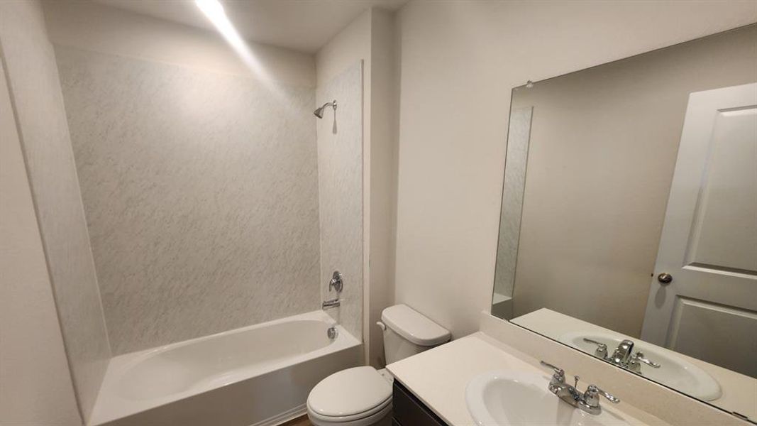 Bathroom featuring a tub/shower combination with a textured surround, single vanity with a white countertop, undermount sink, and a large wall-mounted mirror