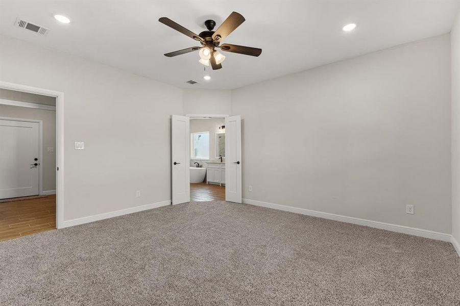 Unfurnished bedroom with light carpet, recessed lighting, a ceiling fan, and ensuite bath