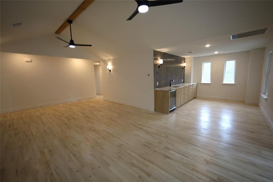 Unfurnished living room featuring light wood floors, a ceiling fan, and wine cooler