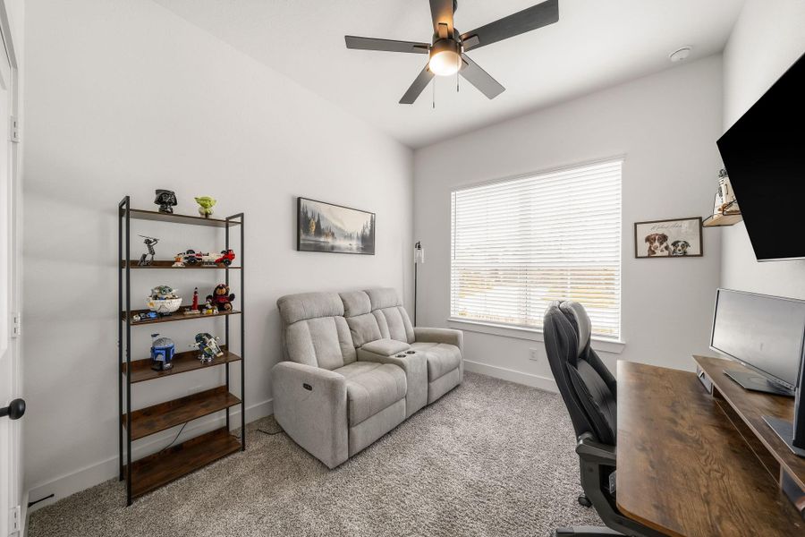 This secondary bedroom offers plush carpet and a pair of windows with blinds overlooking the front yard, allowing natural light to brighten the space while creating a comfortable and refined retreat.