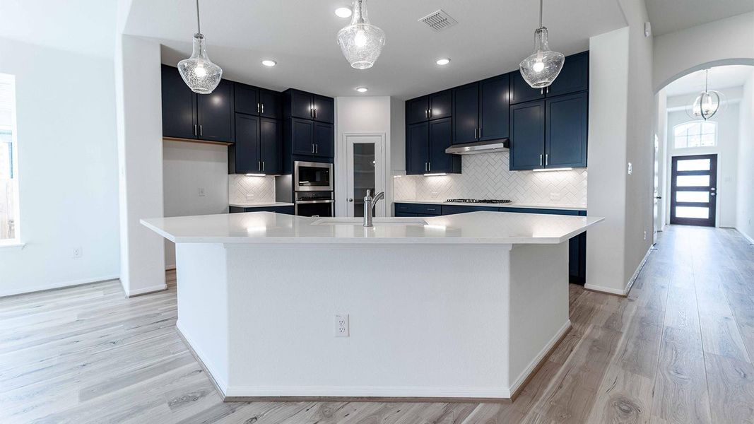 Kitchen featuring arched walkways, decorative light fixtures, a large island, stainless steel appliances, and decorative backsplash