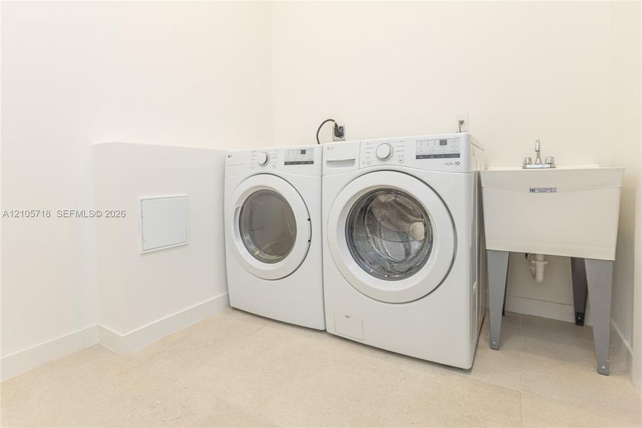 Utility area featuring a deep-basin laundry sink with a dual-handle faucet and dedicated washer and dryer connections