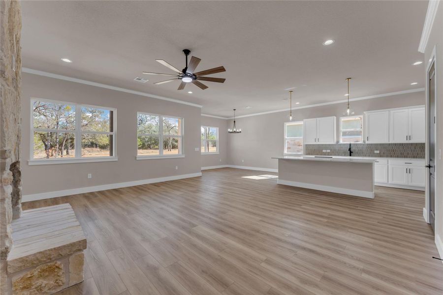 Unfurnished living room with ornamental molding, ceiling fan, light wood-style flooring, and recessed lighting