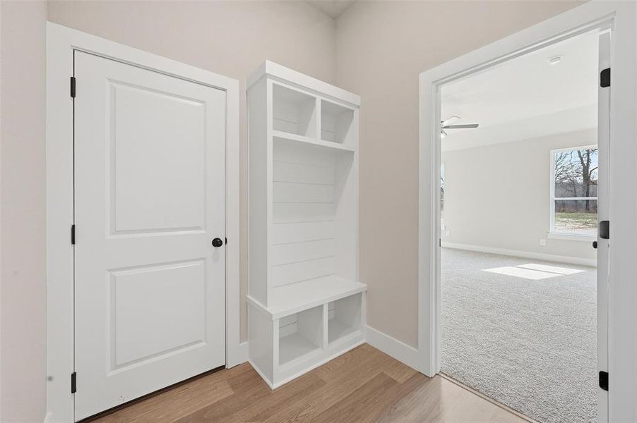 Mudroom with light wood-type flooring and light colored carpet