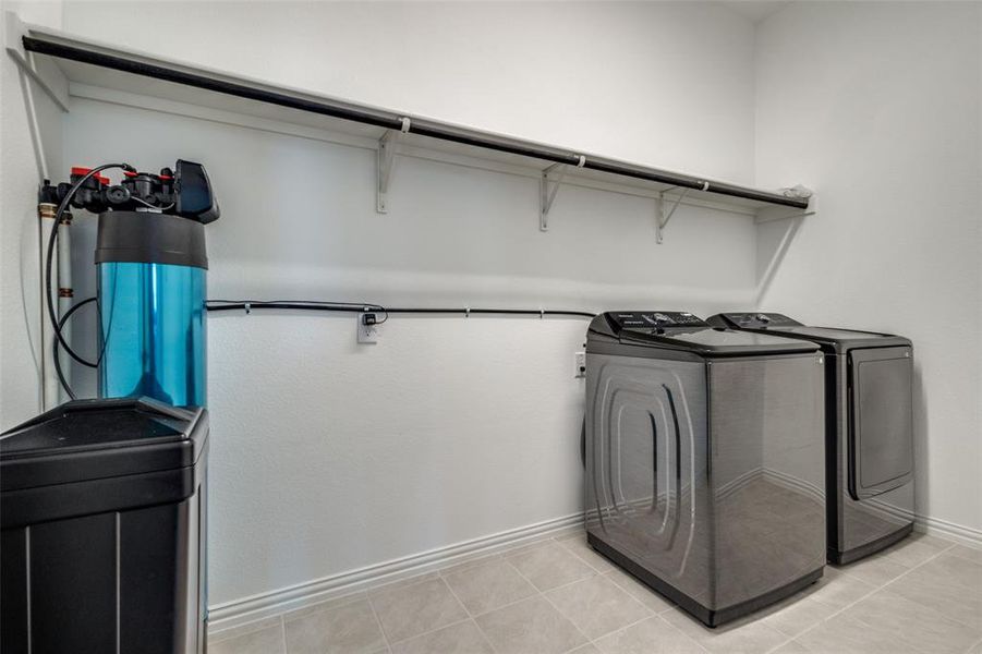 Washroom with light tile patterned floors and independent washer and dryer