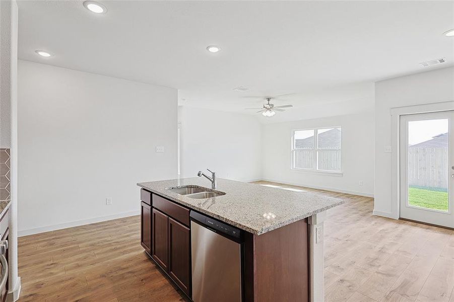 Kitchen with light hardwood / wood-style floors, stainless steel dishwasher, a wealth of natural light, and sink