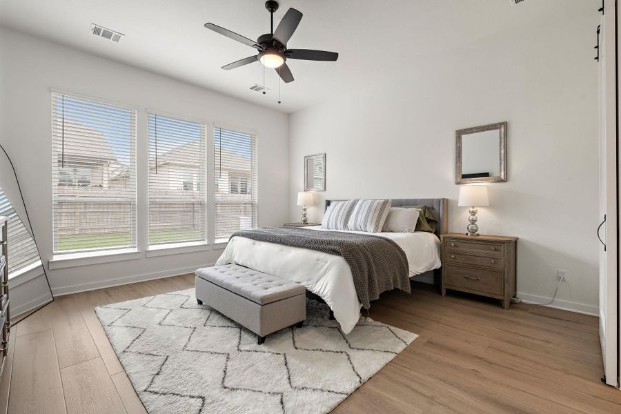 Bright room featuring wood-finish flooring, a contemporary ceiling fan, and three large windows with horizontal blinds