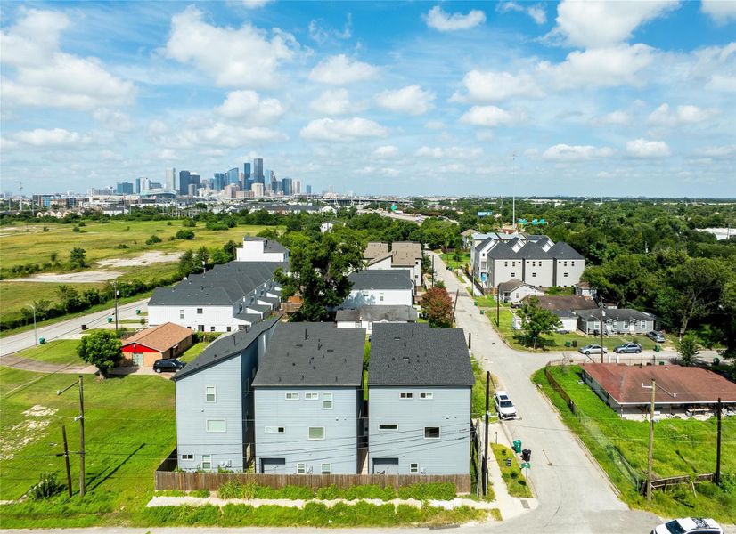 Modern townhouses in a quiet residential area with a view of the city skyline in the background. The neighborhood features green spaces and a mix of contemporary and traditional homes, offering a blend of urban and suburban living.