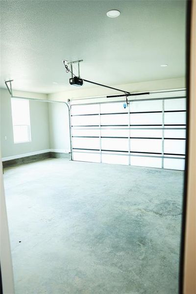 Spacious garage featuring a modern sectional garage door with horizontal frosted glass panels, an automatic door opener, and recessed ceiling lighting