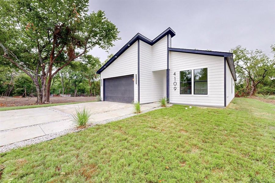Contemporary exterior featuring white siding with dark trim accents, a dark garage door, and a concrete driveway Contemporary exterior featuring white siding with dark trim accents, a dark garage door, and a concrete driveway