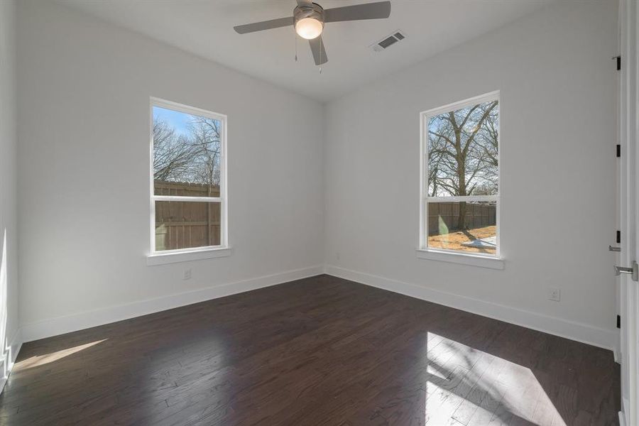 Spare room featuring ceiling fan, plenty of natural light, and dark wood-type flooring