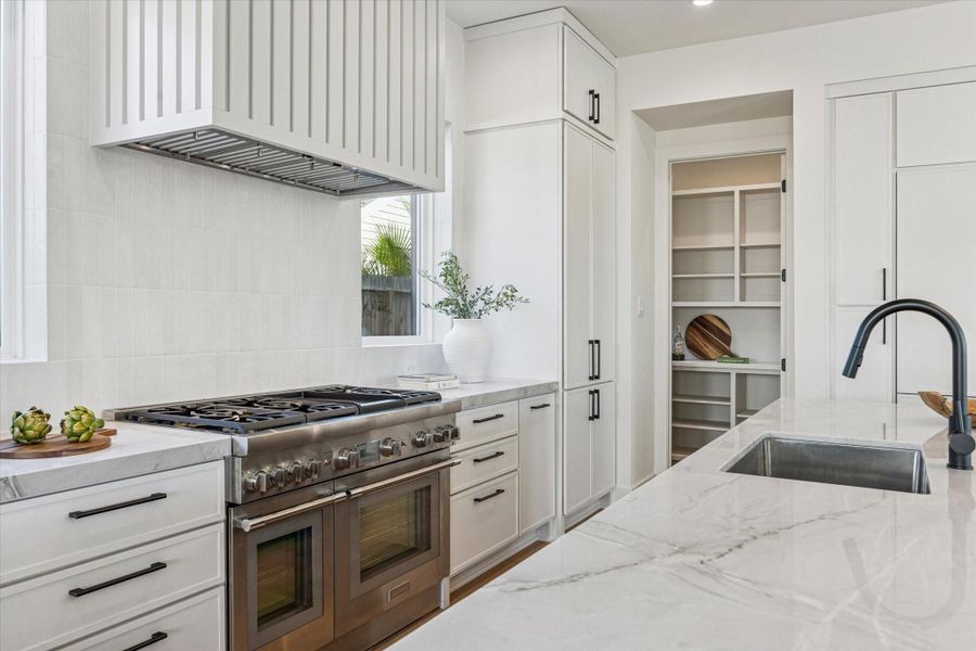 The storage in this kitchen is truly endless! Two large pantries flank the space, complemented by a walk-in pantry perfect for your organizational dreams, plus a niche with additional custom cabinetry.