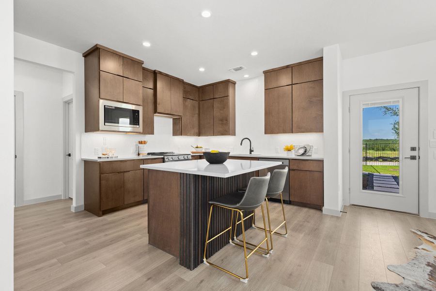 Kitchen featuring a breakfast bar area, quartz countertops, a kitchen island, wood-style floors, and appliances with stainless steel finishes Kitchen featuring a breakfast bar area, quartz countertops, a kitchen island, wood-style floors, and appliances with stainless steel finishes