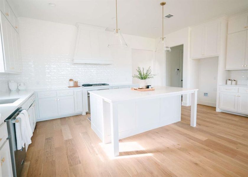 Kitchen featuring white cabinetry, backsplash, and light wood-type flooring