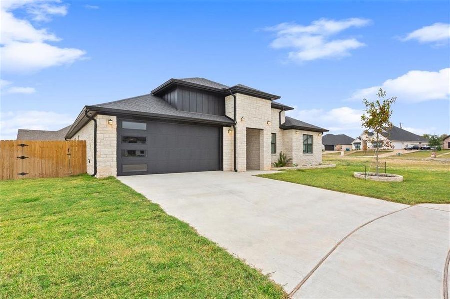 View of front of house featuring concrete driveway, stone siding, a garage, and a gate