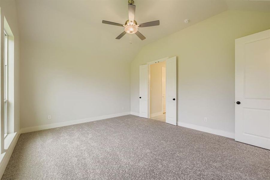 Unfurnished bedroom with vaulted ceiling, light colored carpet, and a ceiling fan