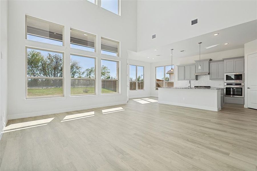 Unfurnished living room featuring a high ceiling and light wood-type flooring