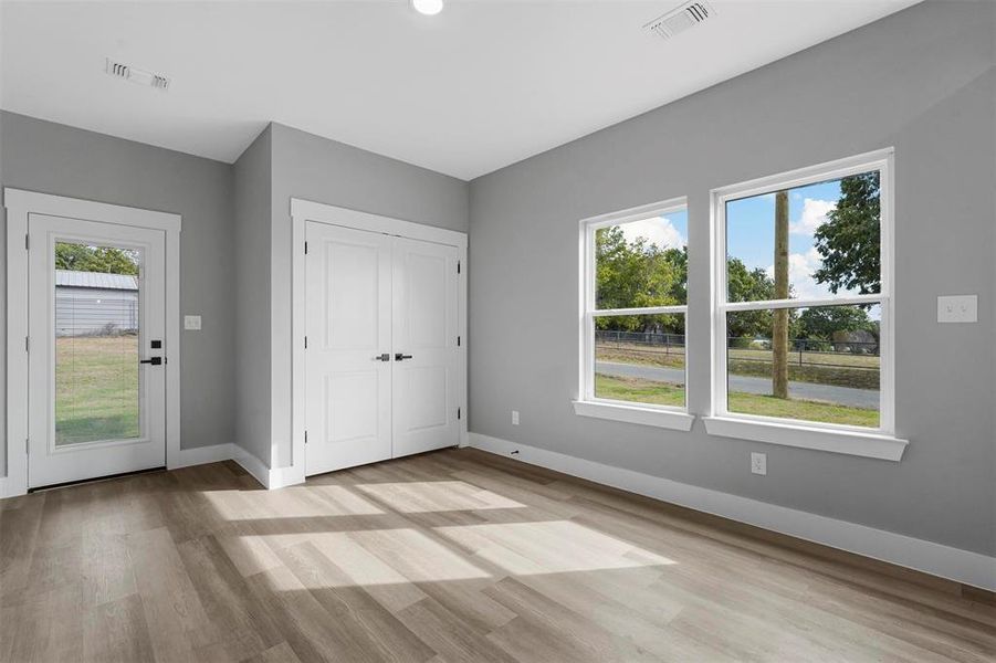 Unfurnished bedroom featuring multiple windows, a closet, and light hardwood / wood-style floors