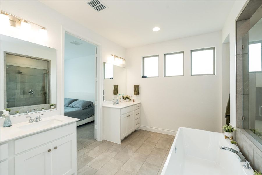 Ensuite bathroom featuring a shower stall, two vanities, a bath, and recessed lighting