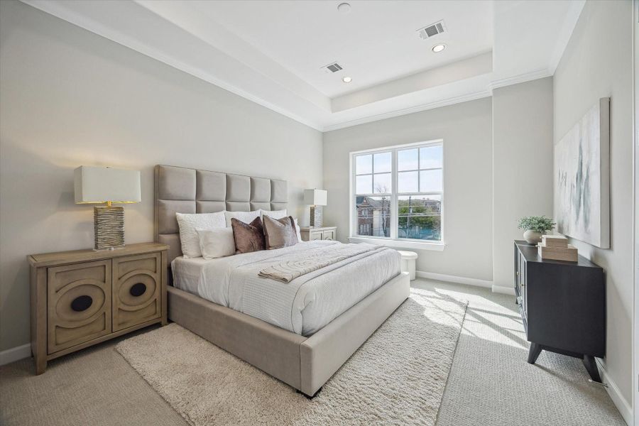 Primary suite offers tray ceiling, recessed lighting, and luxury carpet