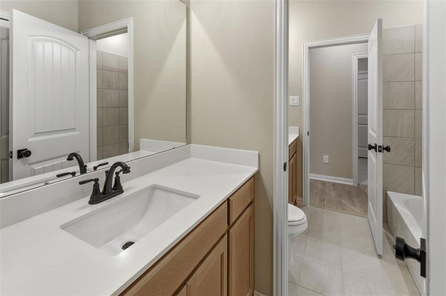 Bathroom vanity featuring an integrated rectangular sink, matte black faucet, and light wood-finish cabinetry
