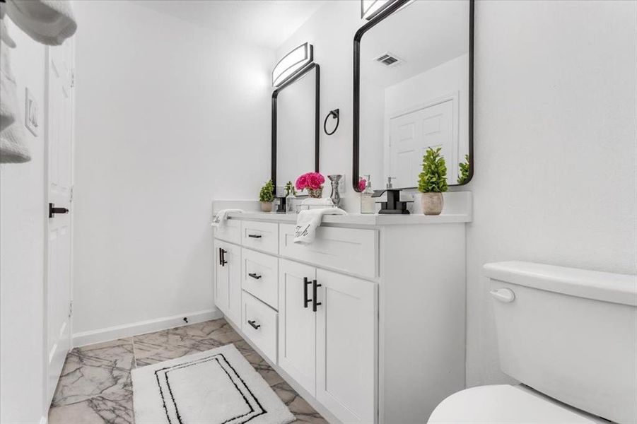 Bathroom with tile patterned flooring, toilet, and double vanity