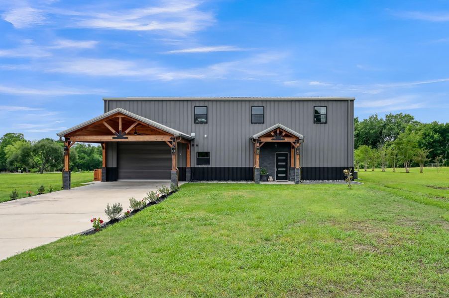 Modern two-story home with a metal exterior, featuring a covered driveway and garage.