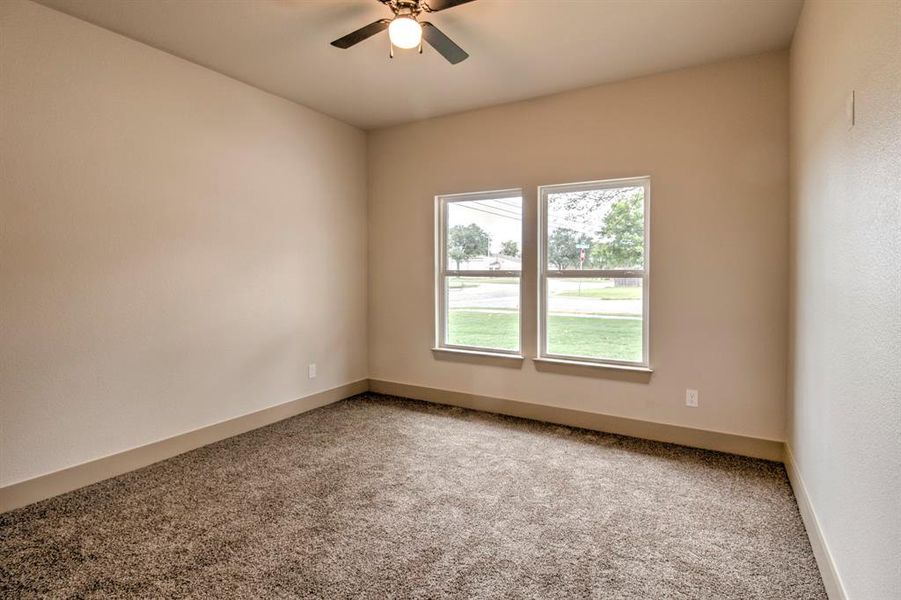 Carpeted spare room with a ceiling fan and baseboards