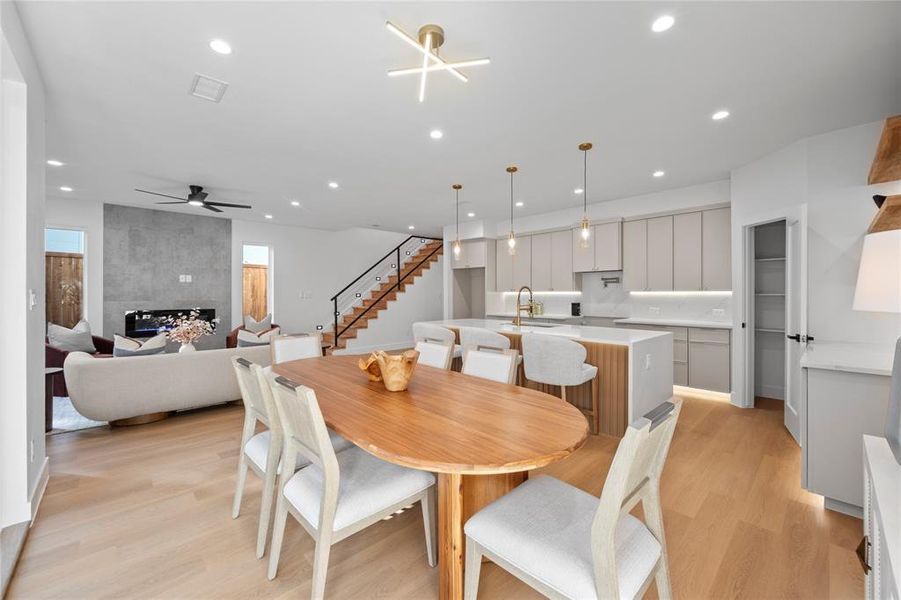 Dining room with sink, ceiling fan, light hardwood / wood-style flooring, and a tile fireplace