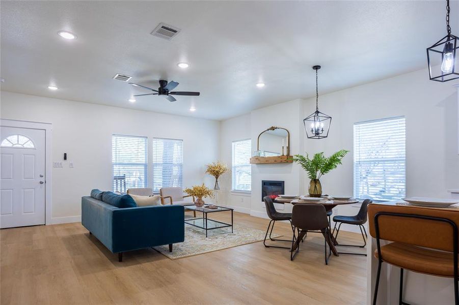 Living room featuring a glass covered fireplace, light wood-type flooring, a ceiling fan, recessed lighting, and healthy amount of natural light