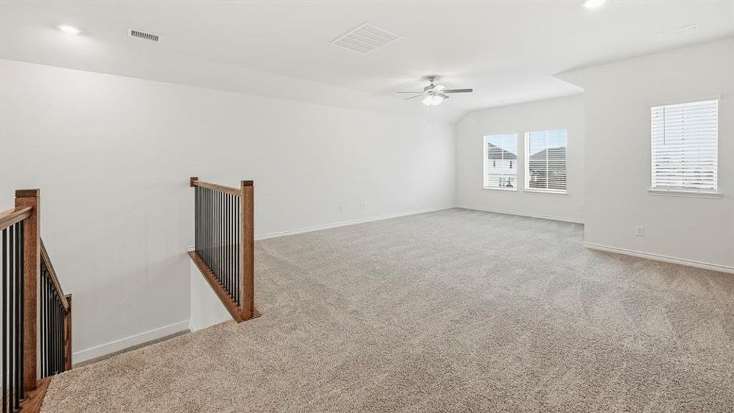 Spacious upper-level room featuring light gray carpet flooring, multiple windows with blinds, a ceiling fan, and recessed lighting