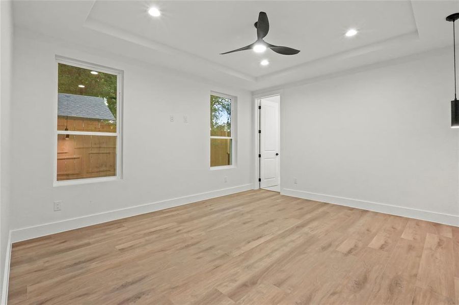 Unfurnished room with a tray ceiling, light wood-style floors, recessed lighting, and a ceiling fan Unfurnished room with a tray ceiling, light wood-style floors, recessed lighting, and a ceiling fan