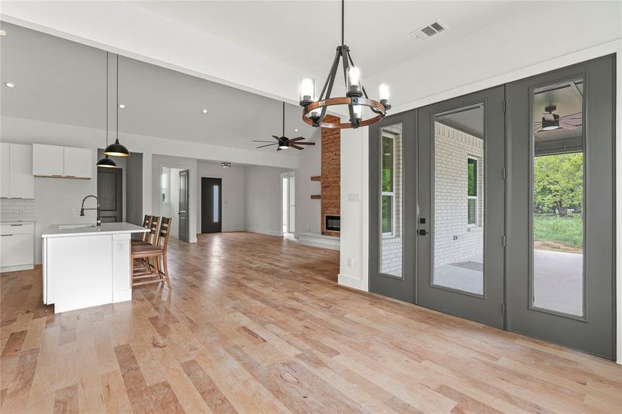 Kitchen with a ceiling fan, white cabinets, french doors, hanging light fixtures, and light wood-style floors