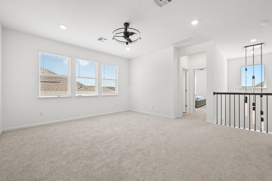 An airy upstairs loft showcases soft carpeting and wide windows framing neighborhood views.
