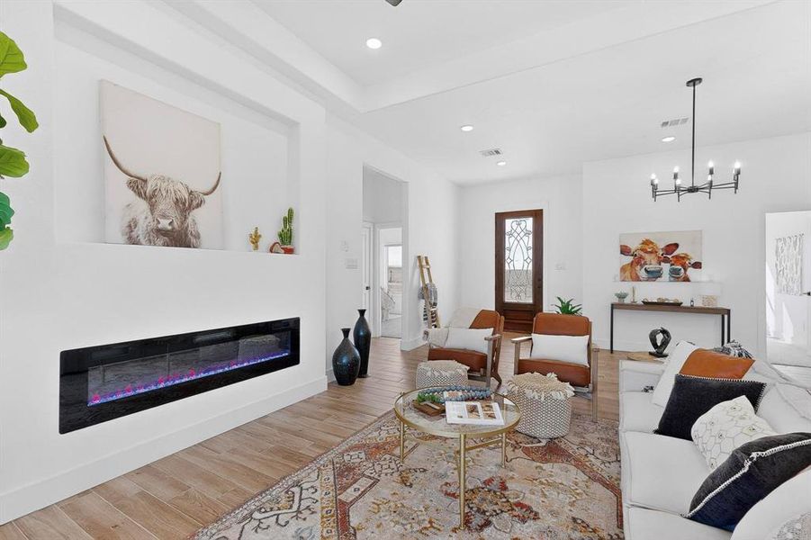 Living area featuring a glass covered fireplace, wood finished floors, recessed lighting, and a chandelier
