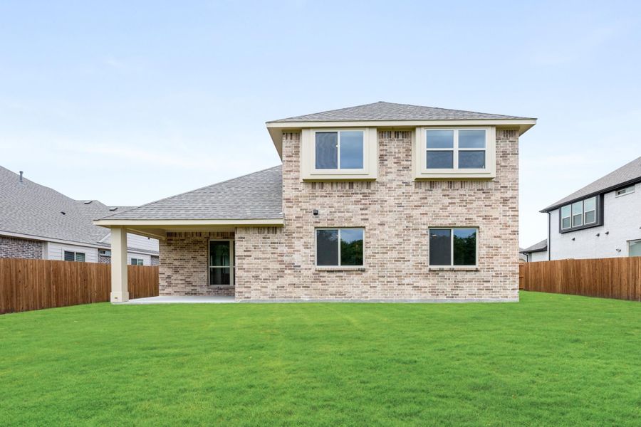 Two-story brick home rear view with covered patio, large backyard, and wood privacy fence Two-story brick home rear view with covered patio, large backyard, and wood privacy fence