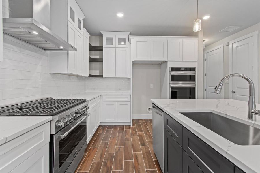 Kitchen with wall chimney range hood, pendant lighting, sink, appliances with stainless steel finishes, and white cabinets