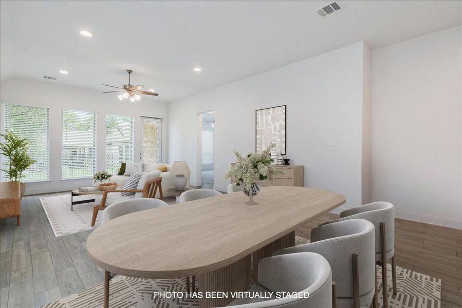 This spacious open-concept living area features light-colored flooring, white walls, and recessed lighting