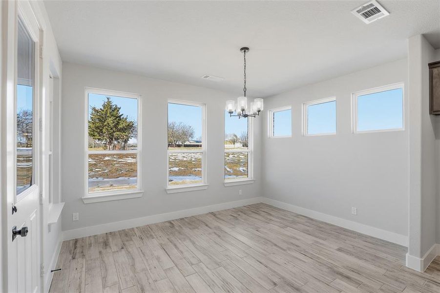 Unfurnished dining area featuring light wood finished floors and a chandelier