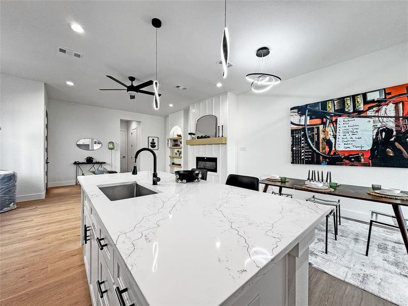 Kitchen featuring a sink, light wood-style floors, light stone counters, a fireplace, and white cabinets