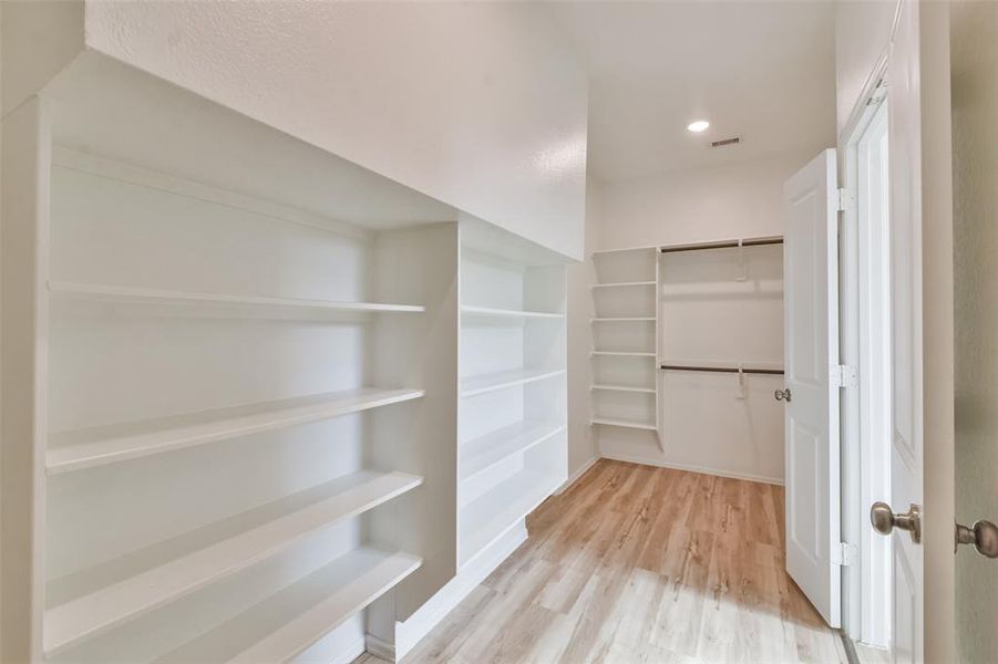 Gorgeous primary walk-in closet with *California Closets* custom cabinetry. Also has a quick and easy access door to the utility room.