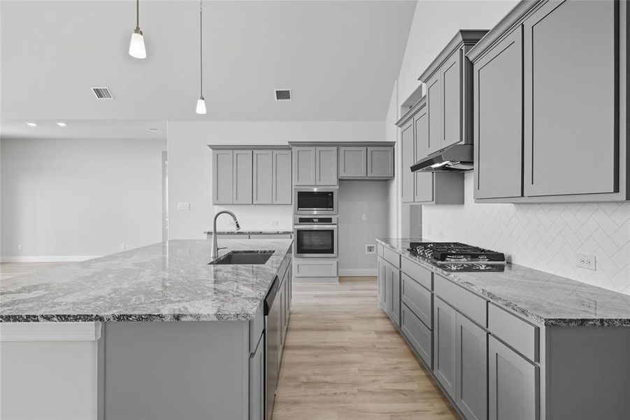 Kitchen with gray cabinets, light stone counters, pendant lighting, stainless steel appliances, and recessed lighting Kitchen with gray cabinets, light stone counters, pendant lighting, stainless steel appliances, and recessed lighting