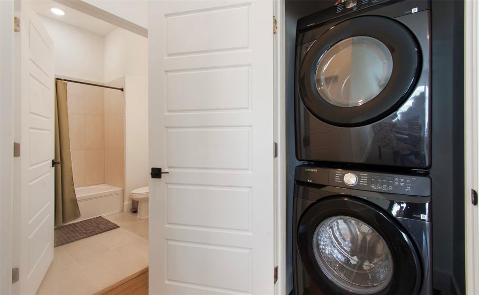 Laundry area featuring stacked washer and dryer and light tile patterned flooring