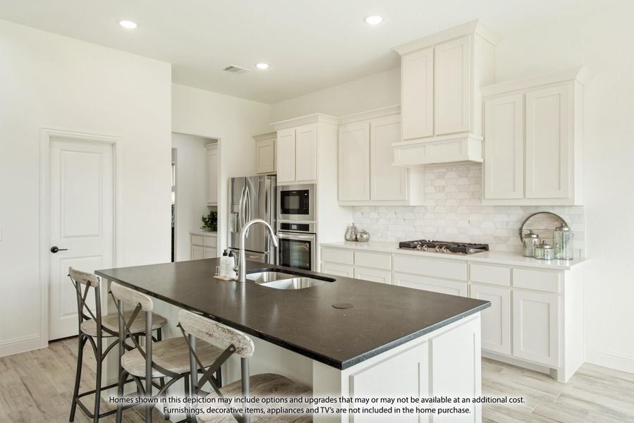 Kitchen with white cabinets, dark island with seating, stainless steel appliances, and white tile backsplash