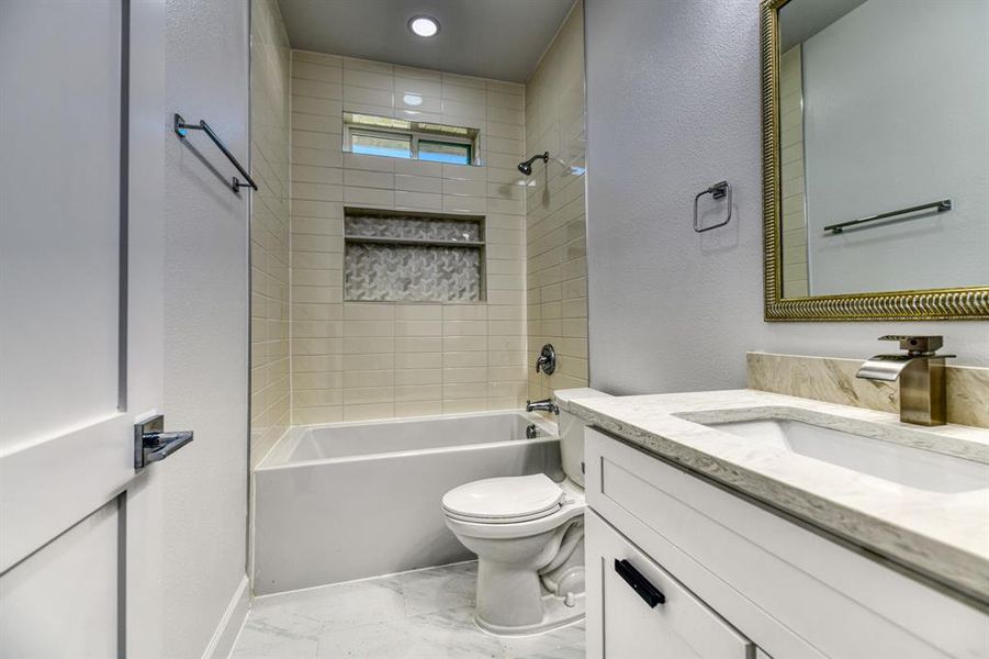 Full bathroom featuring toilet, tiled shower / bath combo, and vanity